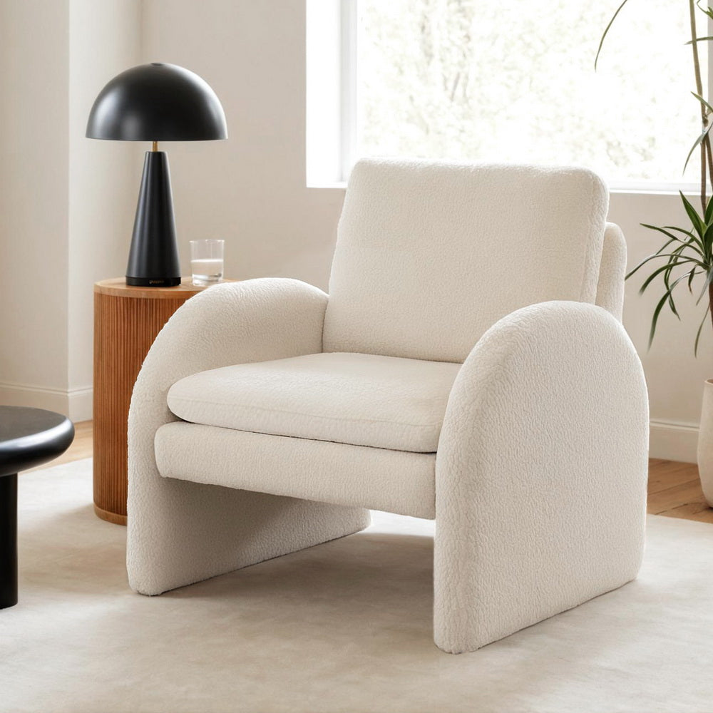 Beige armchair in a modern living room with a black lamp and wooden side table.